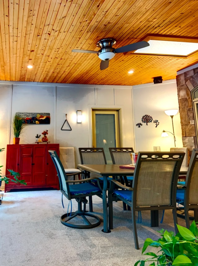 dining space with a skylight, ceiling fan, carpet floors, and wooden ceiling