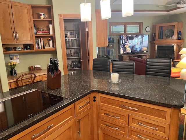 kitchen with decorative light fixtures, ceiling fan, dark stone countertops, and black electric cooktop