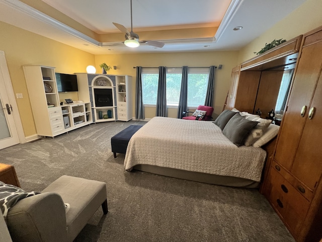 carpeted bedroom featuring a raised ceiling and ceiling fan