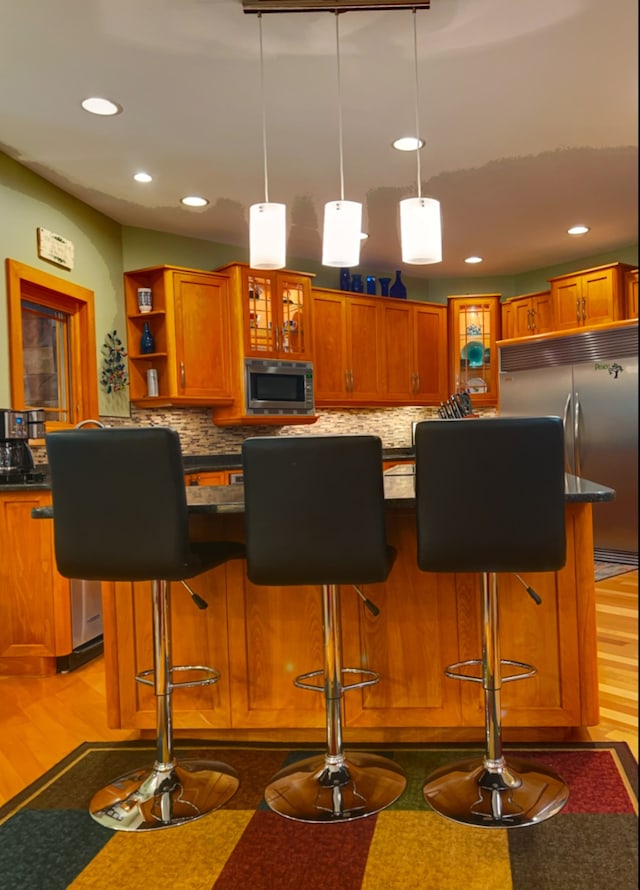 interior space featuring built in appliances, a breakfast bar, a center island, and light hardwood / wood-style floors