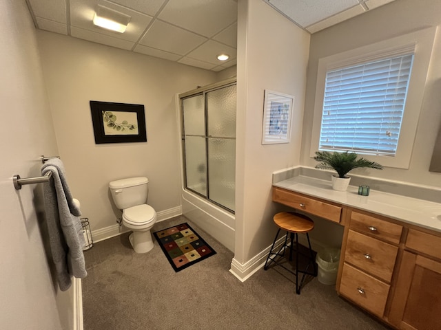 full bathroom with combined bath / shower with glass door, vanity, toilet, and a drop ceiling