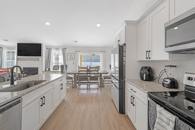 kitchen with white cabinets, a fireplace, stainless steel appliances, and sink