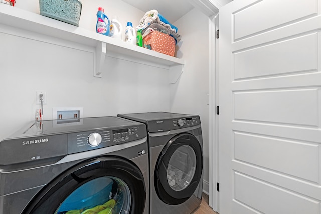 clothes washing area with washing machine and clothes dryer and hardwood / wood-style floors