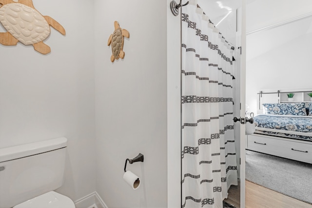 bathroom featuring hardwood / wood-style floors, a shower with curtain, and toilet