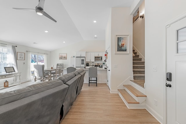 living room with lofted ceiling, ceiling fan, and light hardwood / wood-style floors