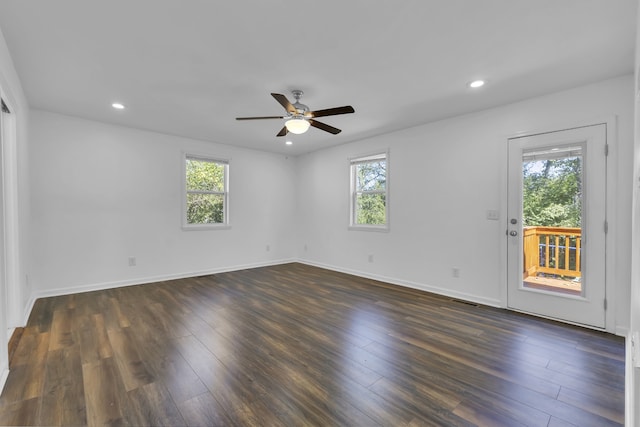 empty room featuring ceiling fan, a wealth of natural light, and dark hardwood / wood-style floors