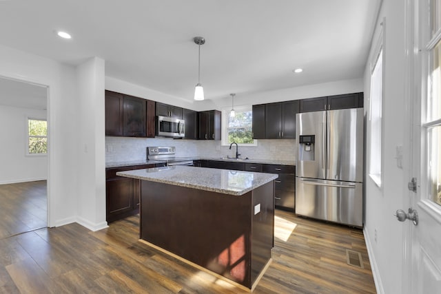 kitchen with a kitchen island, a healthy amount of sunlight, decorative light fixtures, and stainless steel appliances