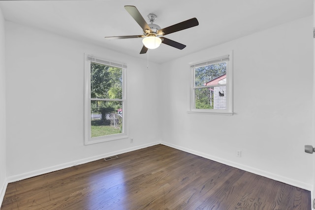 empty room featuring ceiling fan, dark hardwood / wood-style floors, and a healthy amount of sunlight