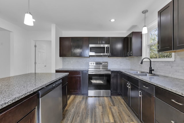 kitchen with dark wood-type flooring, stainless steel appliances, hanging light fixtures, and sink