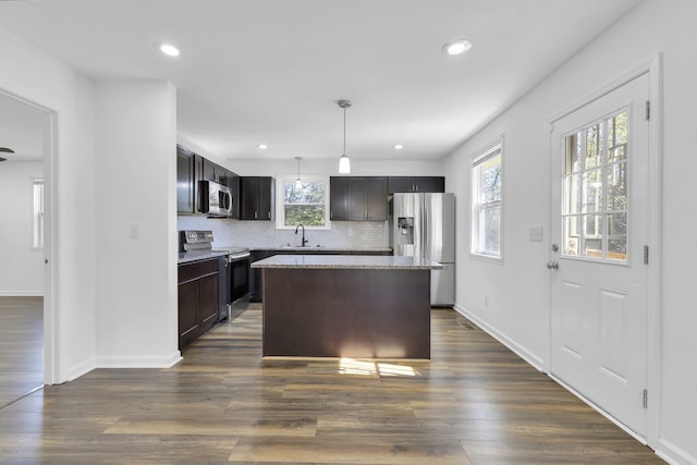 kitchen featuring pendant lighting, a kitchen island, stainless steel appliances, and dark hardwood / wood-style flooring