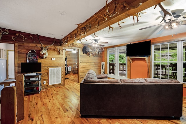 living room with wood walls, ceiling fan, and hardwood / wood-style flooring