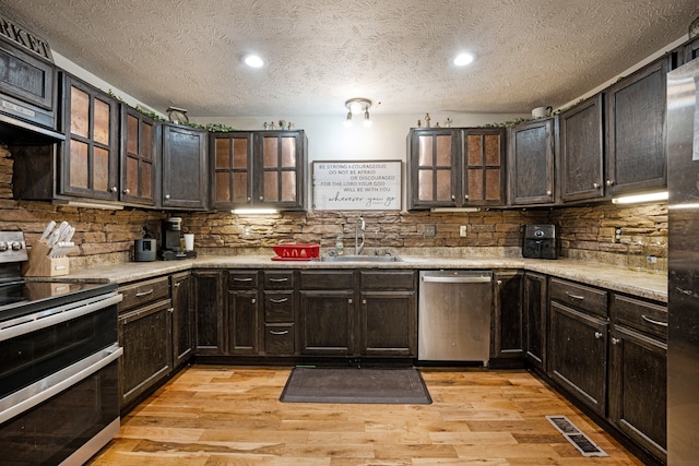 kitchen featuring a textured ceiling, sink, light hardwood / wood-style flooring, and stainless steel appliances