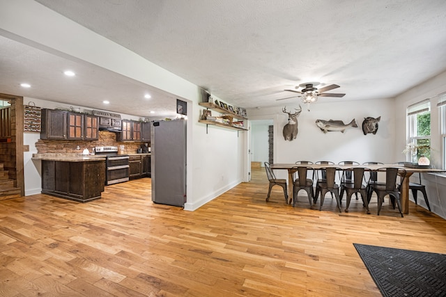 kitchen with dark brown cabinetry, ceiling fan, light hardwood / wood-style flooring, appliances with stainless steel finishes, and decorative backsplash