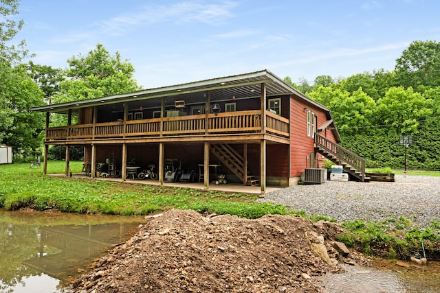 back of house featuring cooling unit and a deck with water view