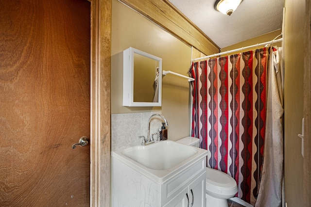 bathroom with a textured ceiling, toilet, decorative backsplash, vanity, and curtained shower