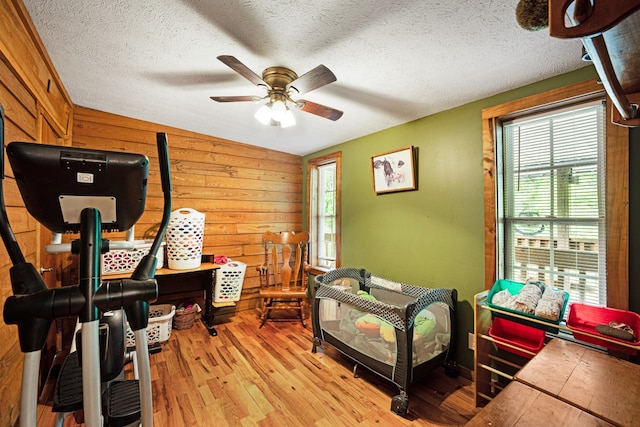 office featuring ceiling fan, a textured ceiling, wood walls, and light hardwood / wood-style floors