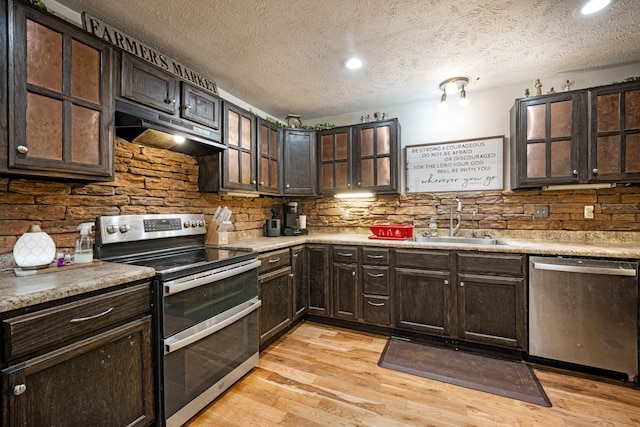 kitchen featuring stainless steel appliances, a textured ceiling, dark brown cabinets, light hardwood / wood-style flooring, and sink