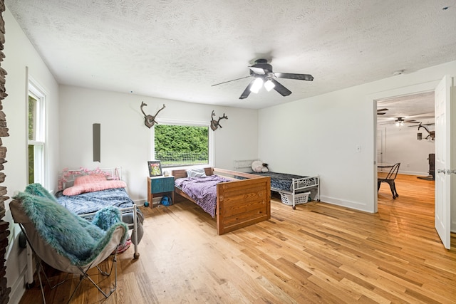 bedroom with ceiling fan, a textured ceiling, and hardwood / wood-style floors