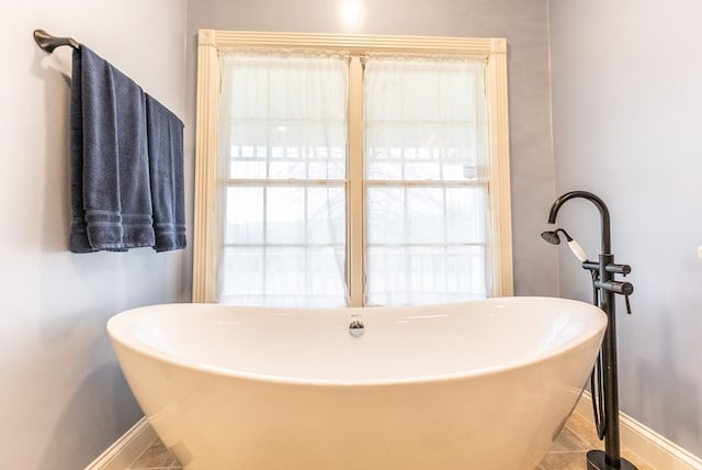 bathroom with a healthy amount of sunlight, tile patterned floors, and a washtub