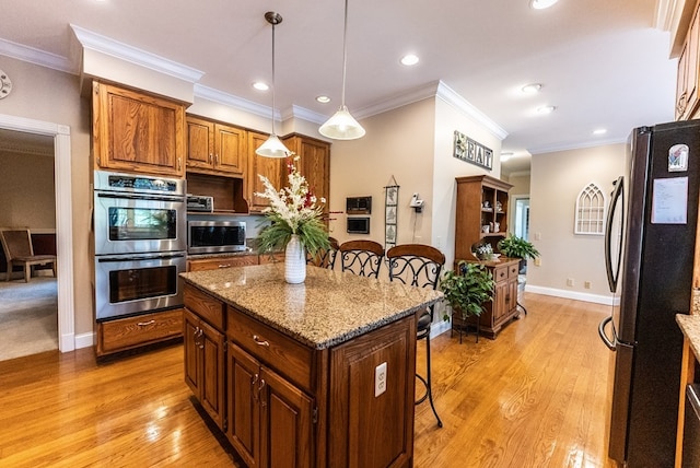 kitchen with a breakfast bar, light hardwood / wood-style flooring, appliances with stainless steel finishes, and a kitchen island