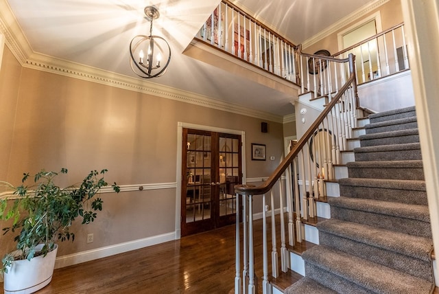 stairs featuring ornamental molding, french doors, a chandelier, and hardwood / wood-style floors