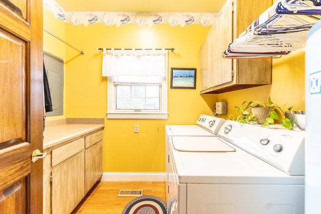 laundry area with washer and dryer, cabinets, and light hardwood / wood-style flooring