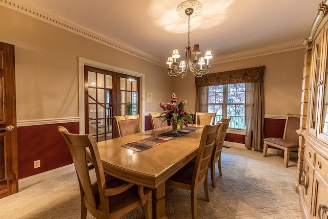 dining space with crown molding, light colored carpet, french doors, and a chandelier