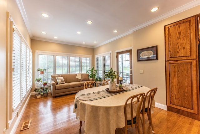 dining space featuring light wood-type flooring and ornamental molding