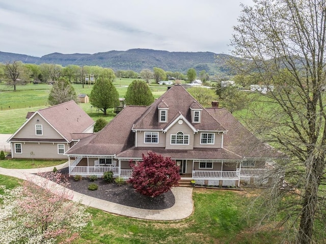 exterior space with a mountain view, a front lawn, and a porch