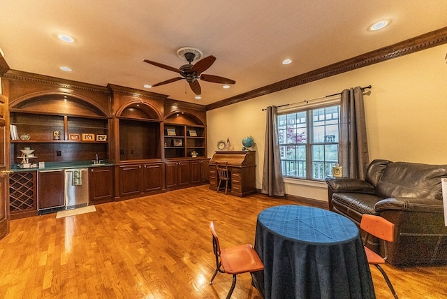 living room with ceiling fan, ornamental molding, sink, and light hardwood / wood-style flooring