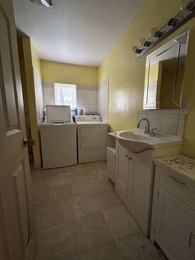 clothes washing area with washing machine and dryer, sink, and cabinets