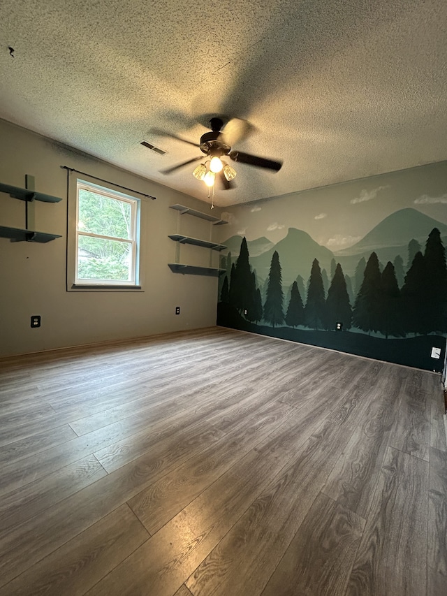 unfurnished room with ceiling fan, wood-type flooring, and a textured ceiling