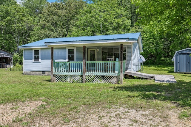 163 Longbranch Rd, Hohenwald, TN 38462 - view of front of home with a porch, a front yard, metal roof, a storage shed, and an outbuilding