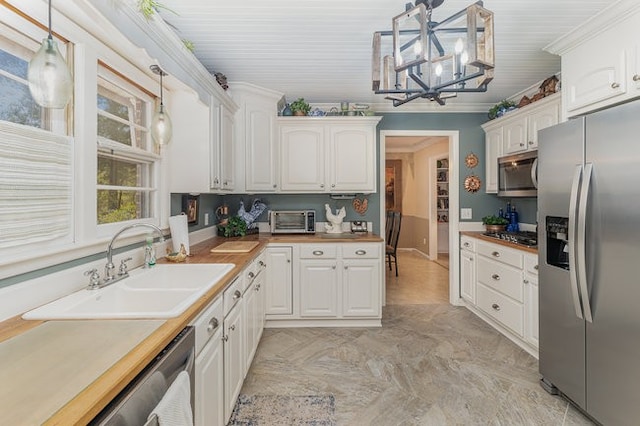 kitchen featuring a chandelier, decorative light fixtures, stainless steel appliances, wood counters, and white cabinets