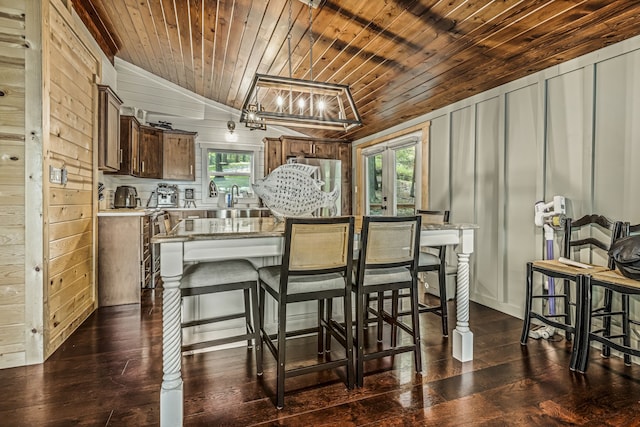 dining space featuring wood walls, wooden ceiling, and a healthy amount of sunlight