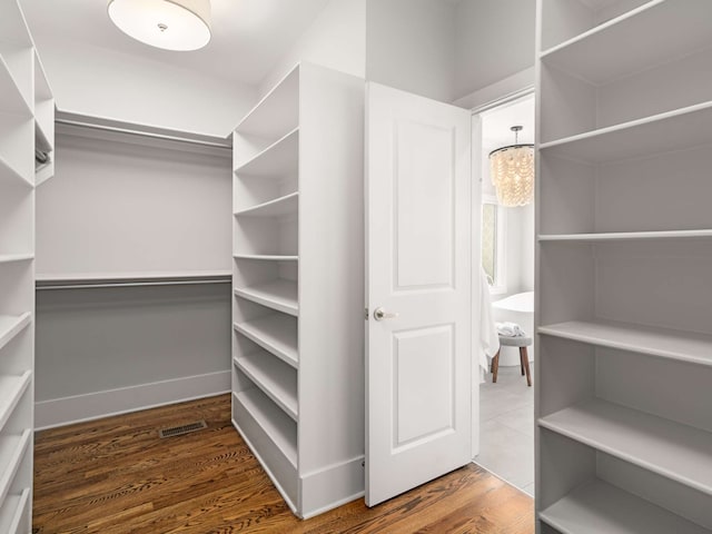 walk in closet with an inviting chandelier and dark hardwood / wood-style floors