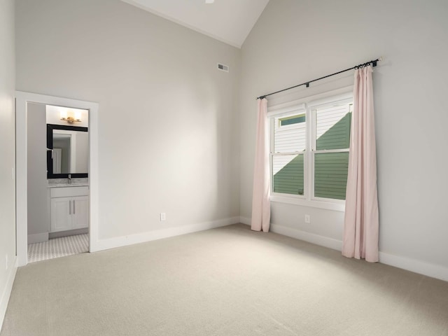 carpeted empty room featuring high vaulted ceiling