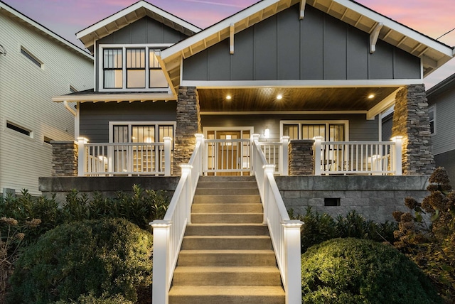 view of front of property featuring covered porch, board and batten siding, and stairs