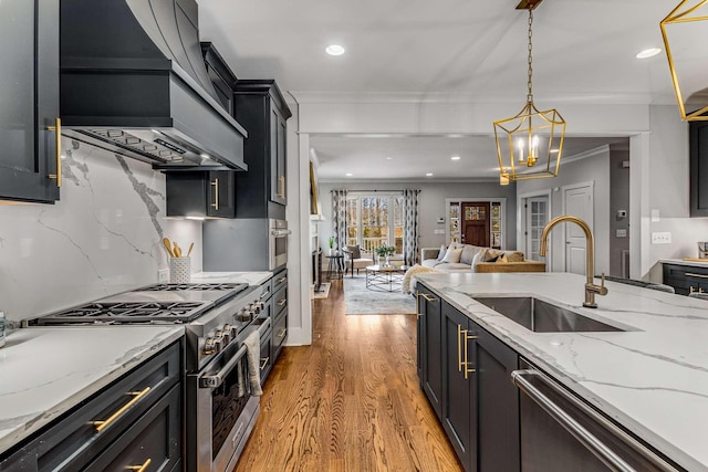 kitchen featuring pendant lighting, sink, appliances with stainless steel finishes, light stone countertops, and custom exhaust hood