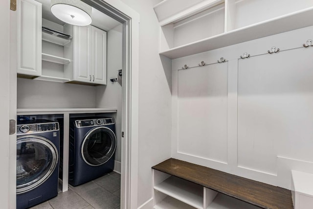 laundry room featuring washer and clothes dryer, cabinets, and light tile patterned flooring