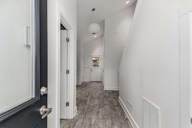 corridor featuring hardwood / wood-style flooring and vaulted ceiling