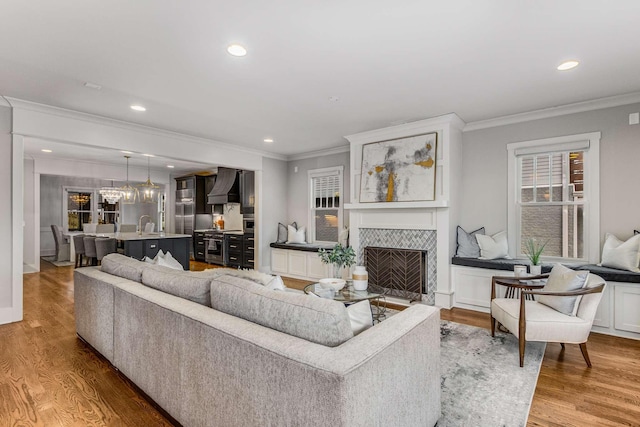 living room with hardwood / wood-style flooring, ornamental molding, and a tile fireplace