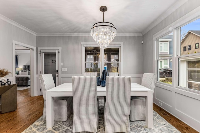 dining space featuring hardwood / wood-style flooring, ornamental molding, and a notable chandelier