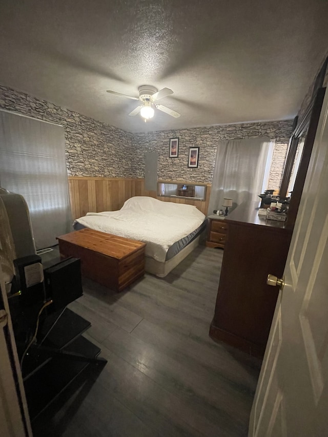 bedroom featuring ceiling fan, dark hardwood / wood-style floors, and a textured ceiling