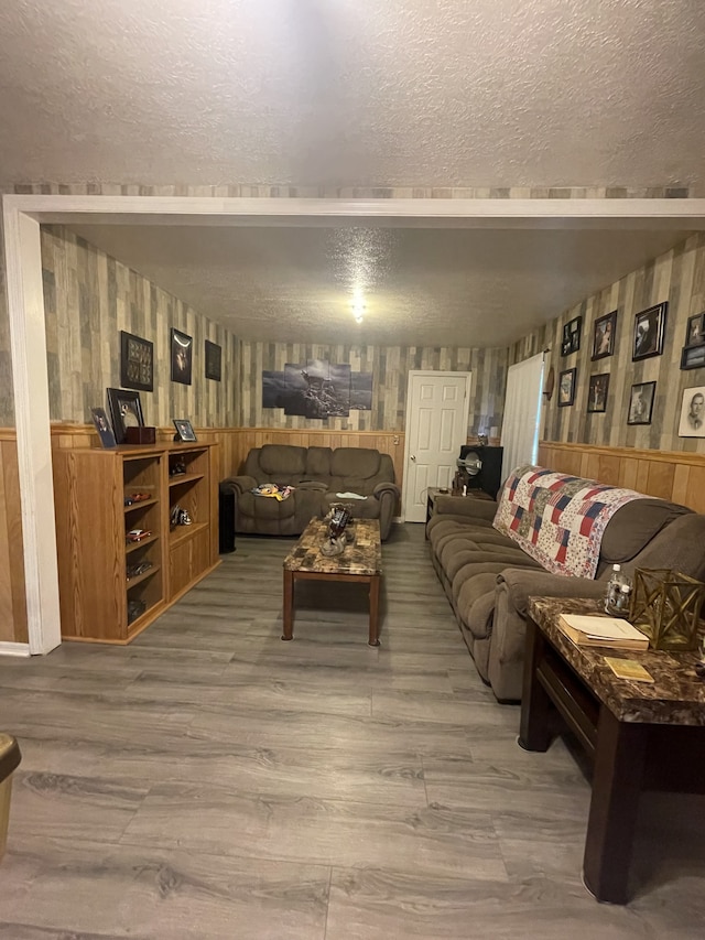 living room with a textured ceiling, hardwood / wood-style flooring, and wooden walls