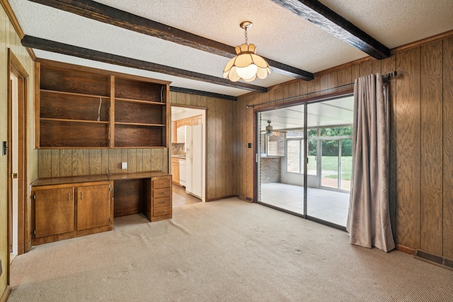 interior space with wood walls, beam ceiling, light carpet, and a textured ceiling