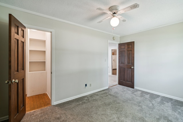 unfurnished bedroom with ceiling fan, carpet, crown molding, and a textured ceiling