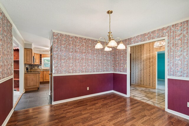 spare room with crown molding, dark wood-type flooring, a textured ceiling, and ceiling fan with notable chandelier