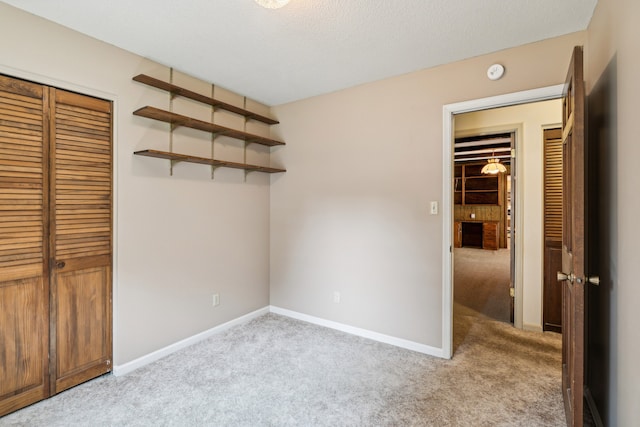 unfurnished bedroom featuring a textured ceiling, a closet, and light carpet