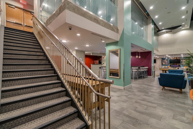 stairs with recessed lighting, baseboards, and a towering ceiling